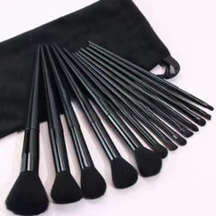 A set of black makeup brushes with black bristles and a matching black velvet pouch, arranged on a light background.