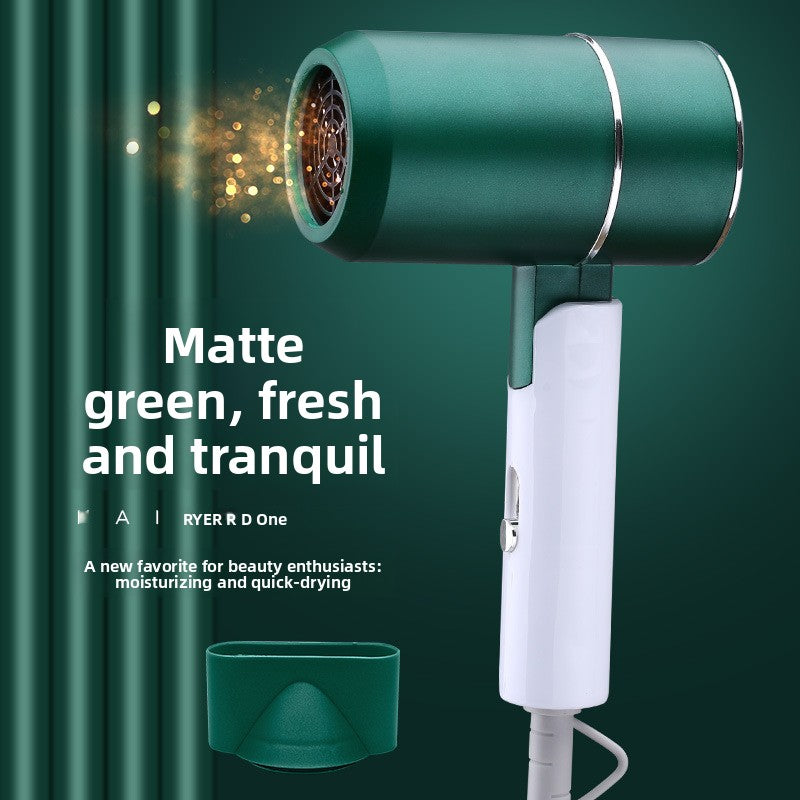 Matte green hair dryer with a white handle and a matching green concentrator nozzle, shown against a dark green textured background with promotional text and golden light effects.